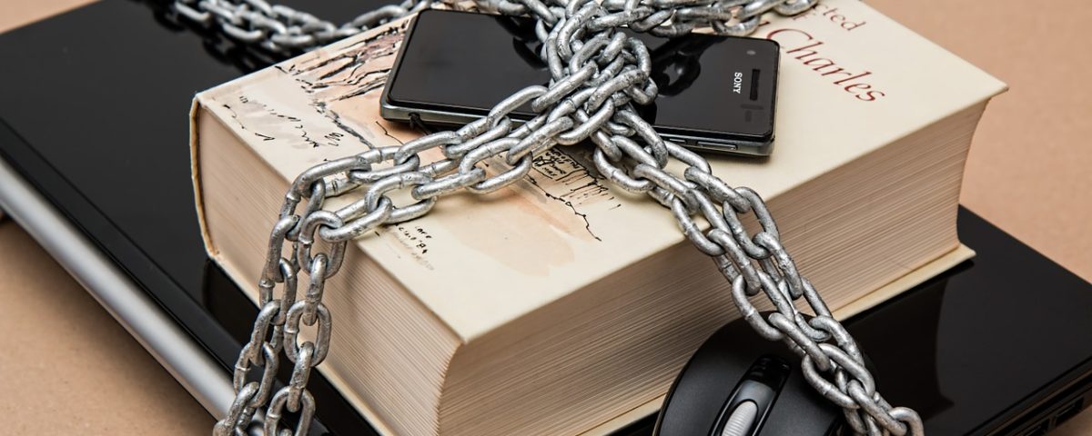 A laptop, book, and cellphone chained