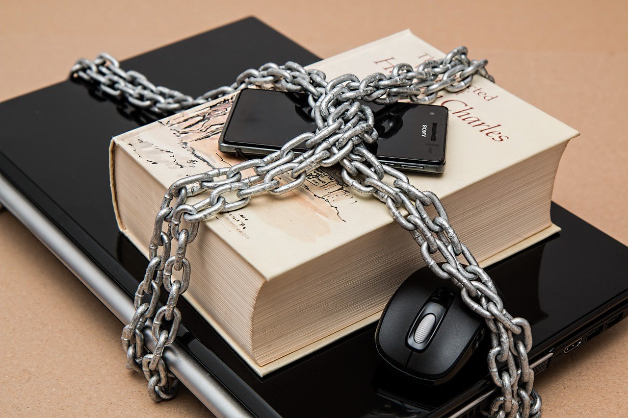 A laptop, book, and cellphone chained