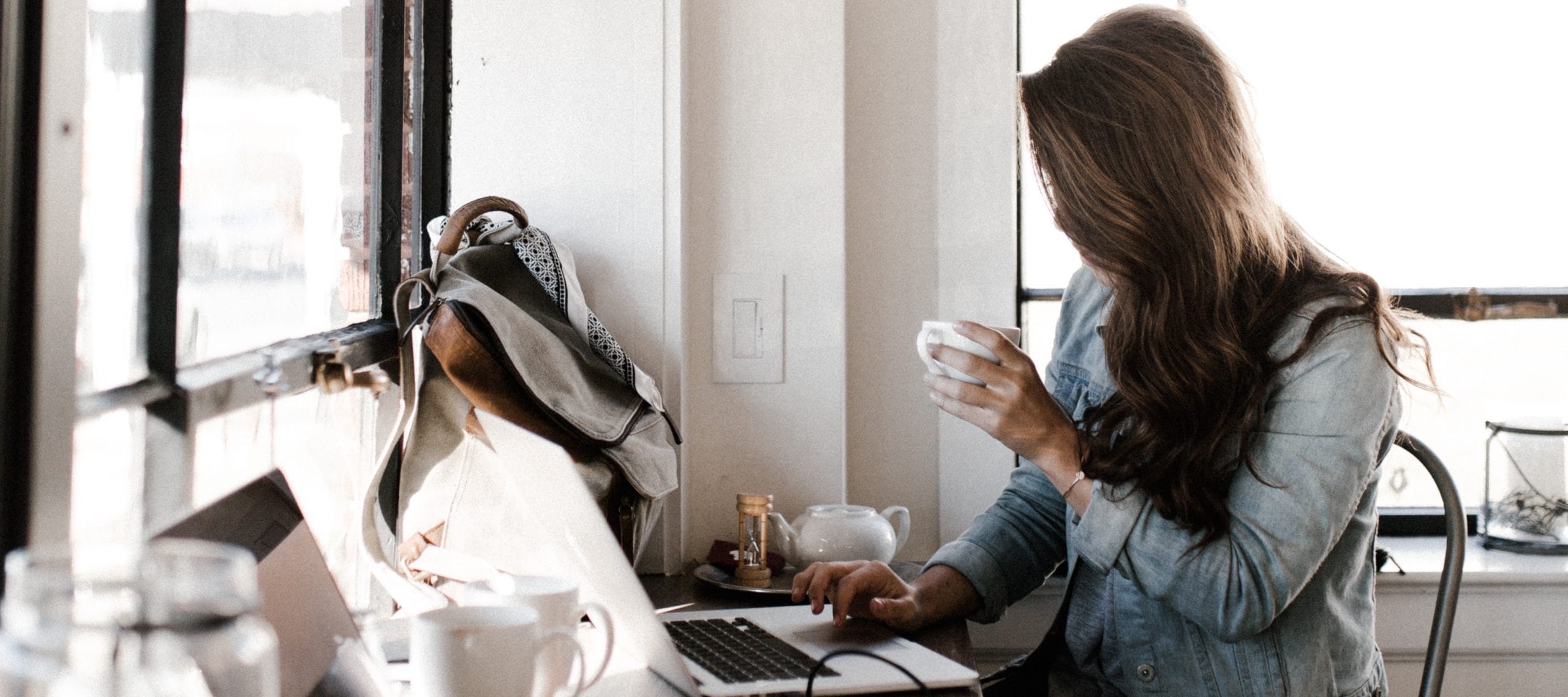 A woman drinking coffee working on her laptop