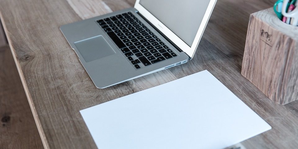 A laptop and a blank page on a desk