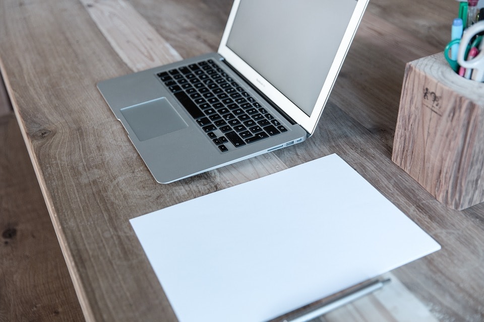 A laptop and a blank page on a desk