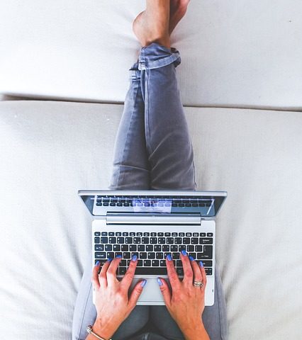A woman sitting on a bad with her laptop
