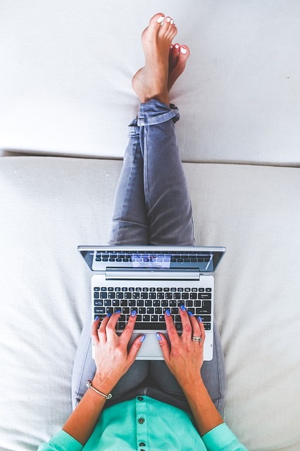 A woman sitting on a bad with her laptop