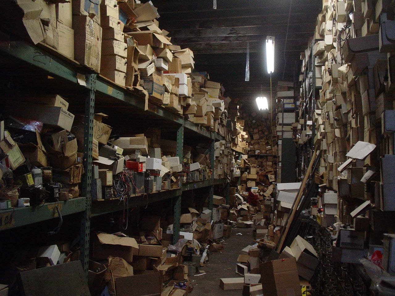 a messy storage room with three shelves of boxes spilling over