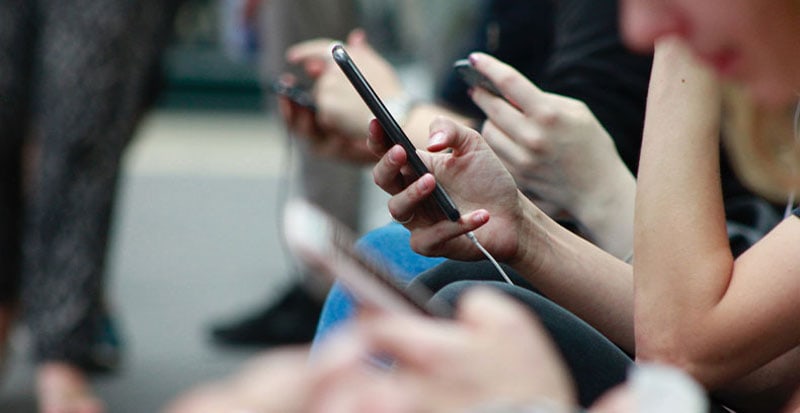 a line of people's hands holding cellphones