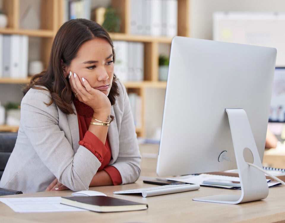A frustrated women staring at her laptop in her office