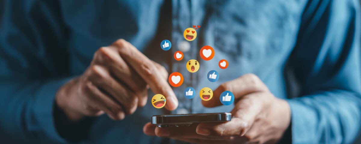 A person scrolling on social media with reactions floating above the phone
