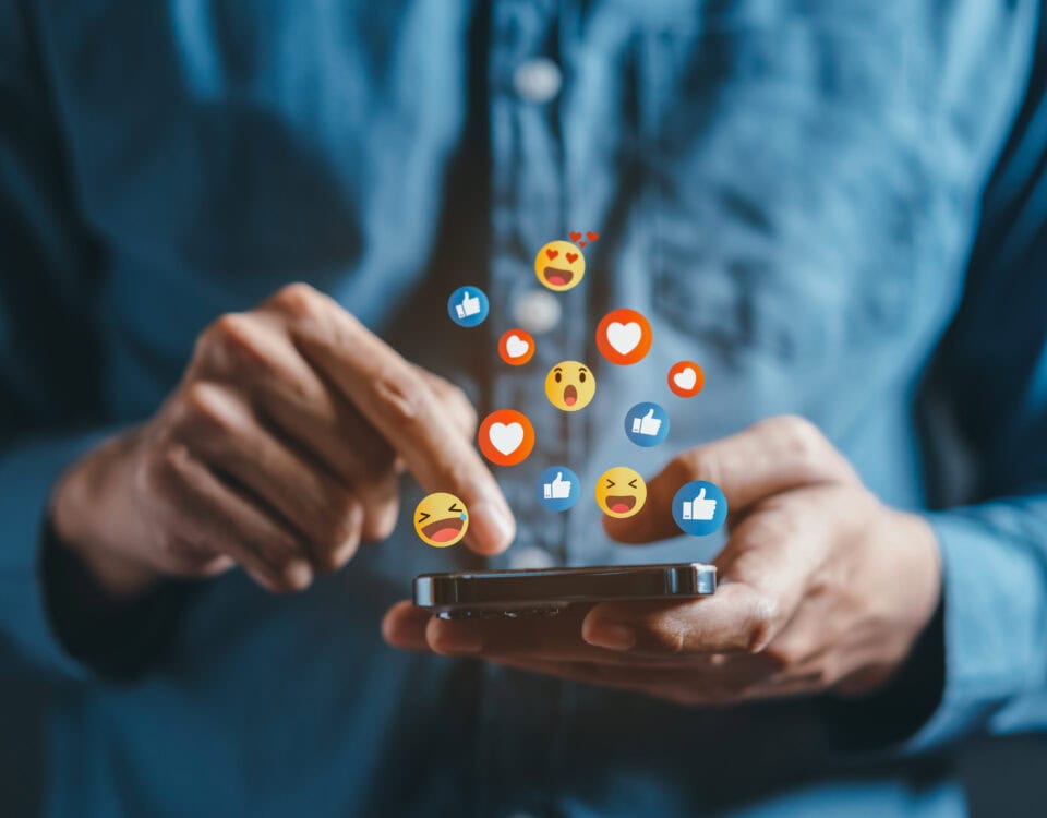 A person scrolling on social media with reactions floating above the phone